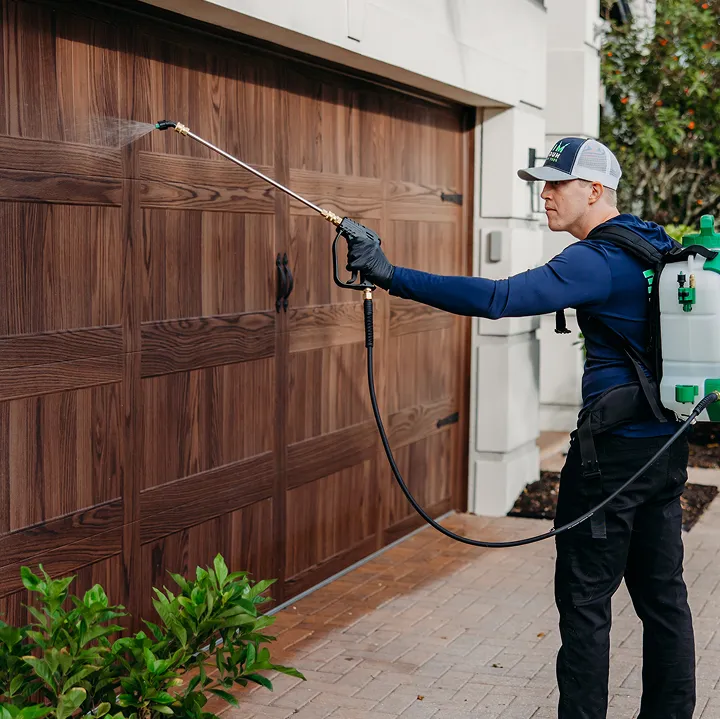 Pest control technician applying termite treatment to a home exterior