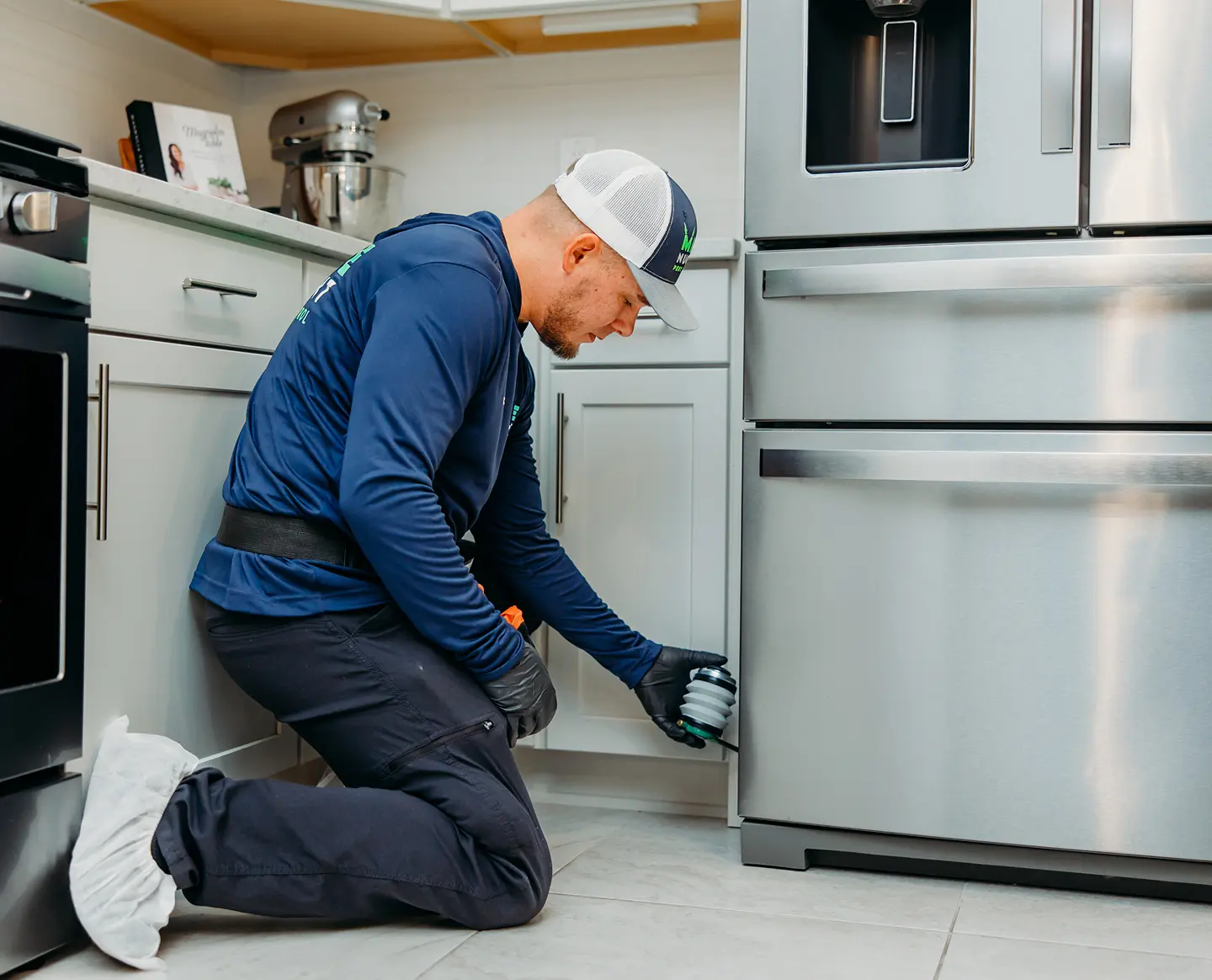 Pest control worker in kitchen by fridge
